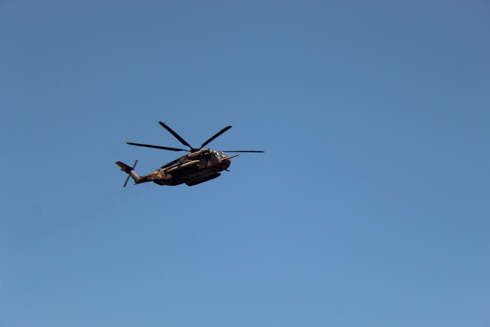 a helicopter flying through a blue sky on a sunny day