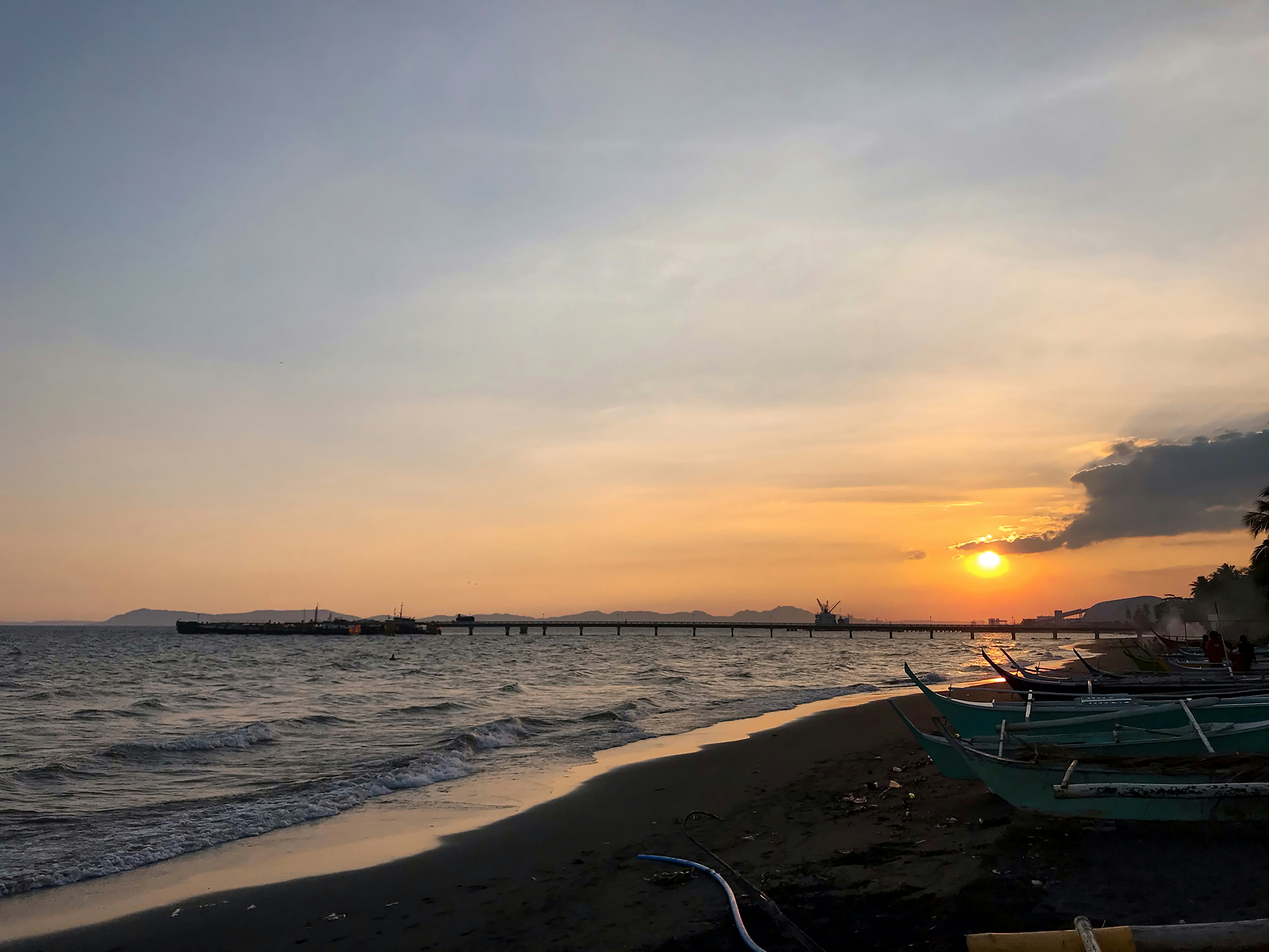 Plage de Dakar au coucher du soleil, pêcheurs sur pirogues colorées, ciel orange