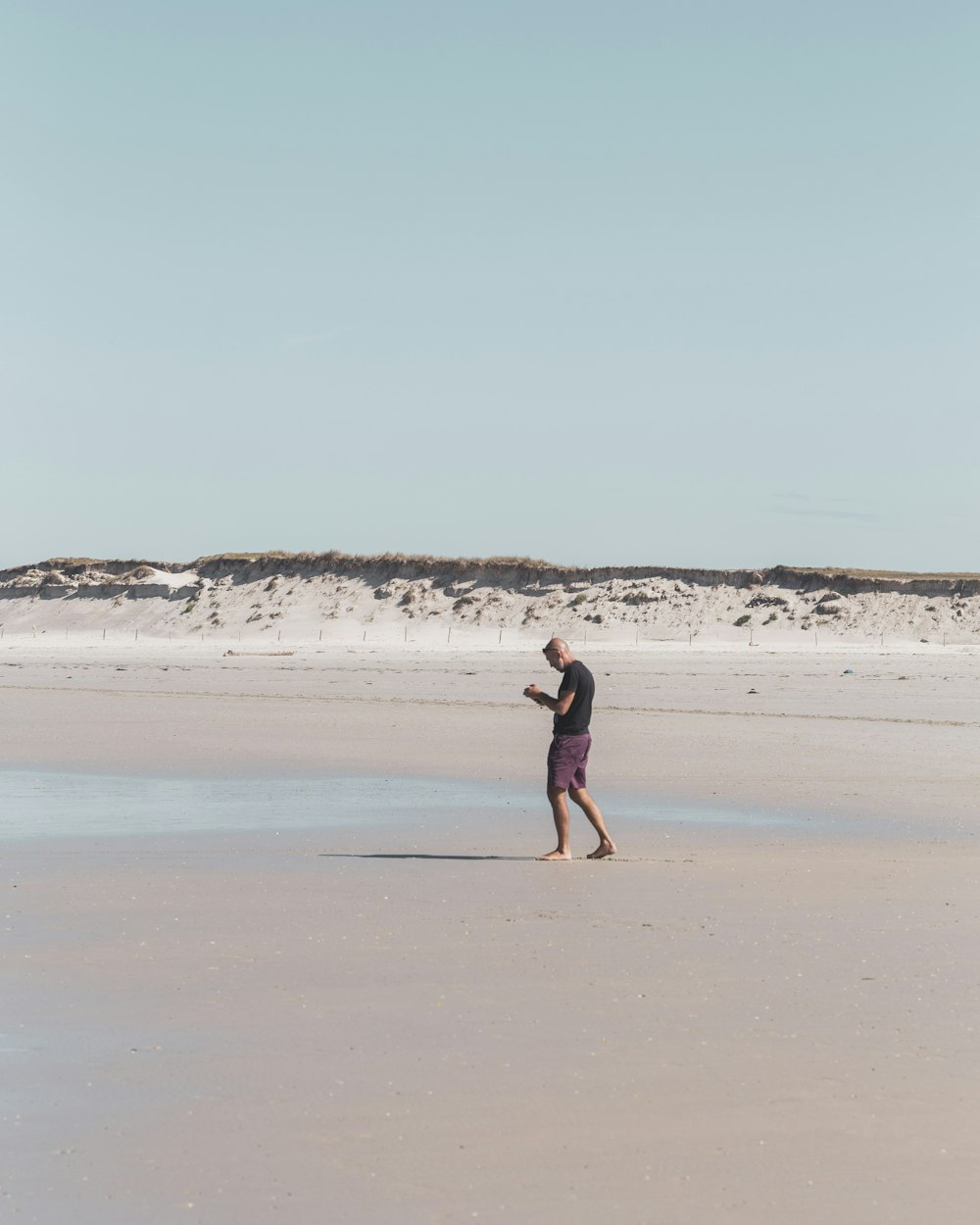 woman in black dress walking on beach during daytime