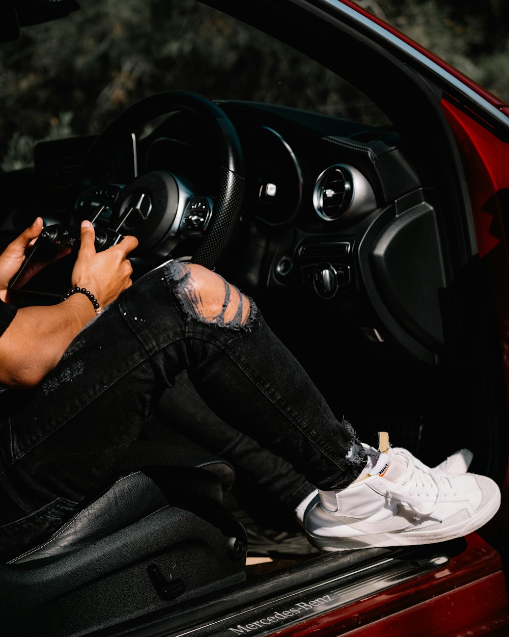 person in black denim jeans and white nike sneakers sitting on car seat