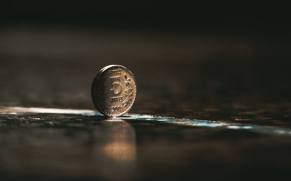 silver round coin on brown wooden table