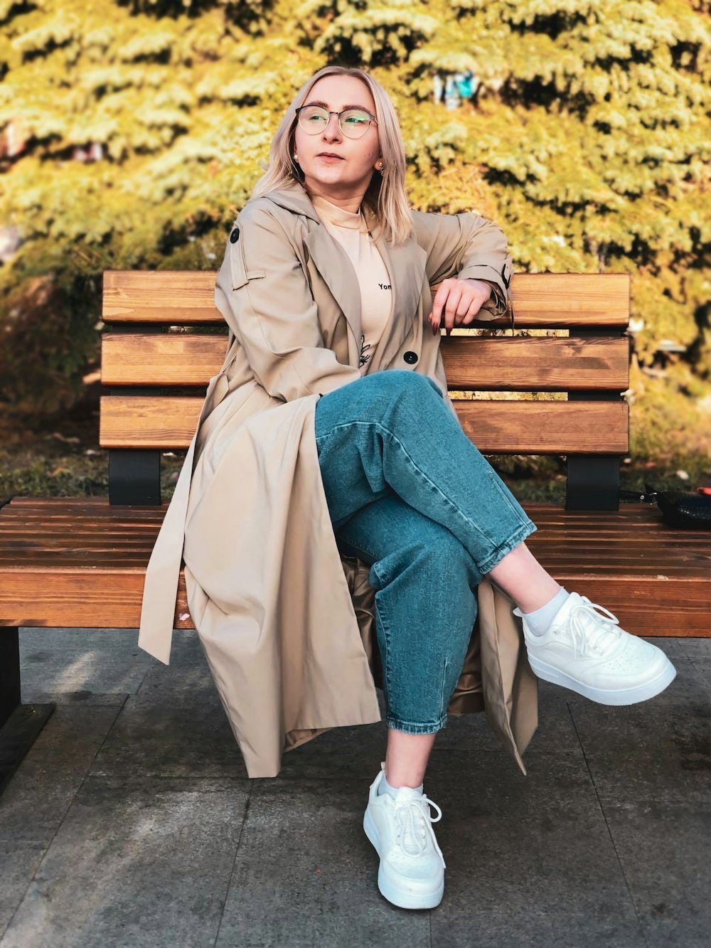 woman in brown coat sitting on brown wooden bench