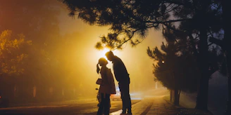 Two silhouettes leaning in close, sharing a playful moment in a lively urban setting at night.