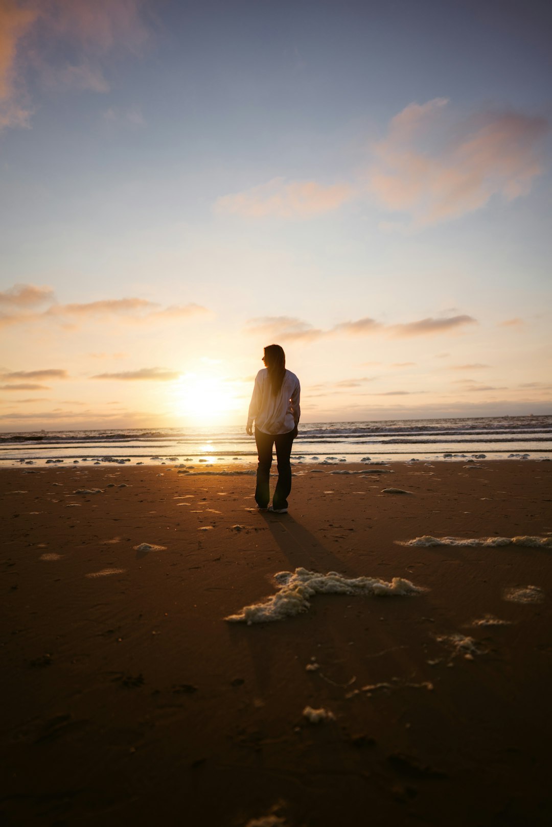 man in white long sleeve shirt and gray pants standing on beach during daytime