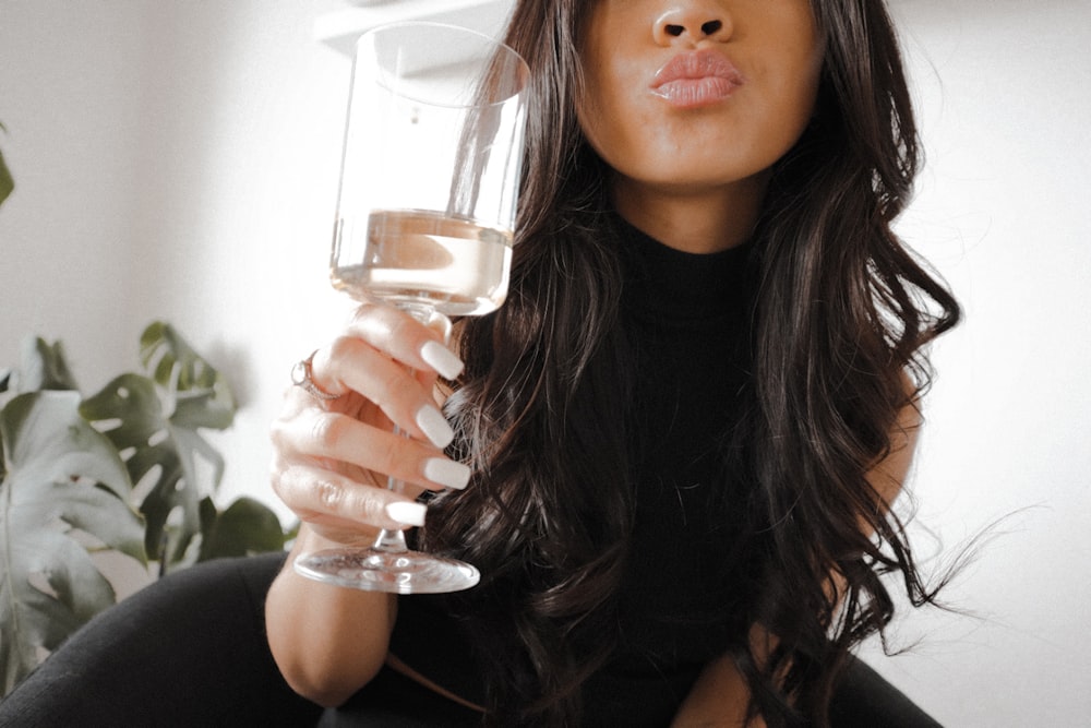 woman in black tank top holding clear drinking glass