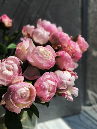 Close-up of a pastel pink peony bouquet bathed in soft natural light.