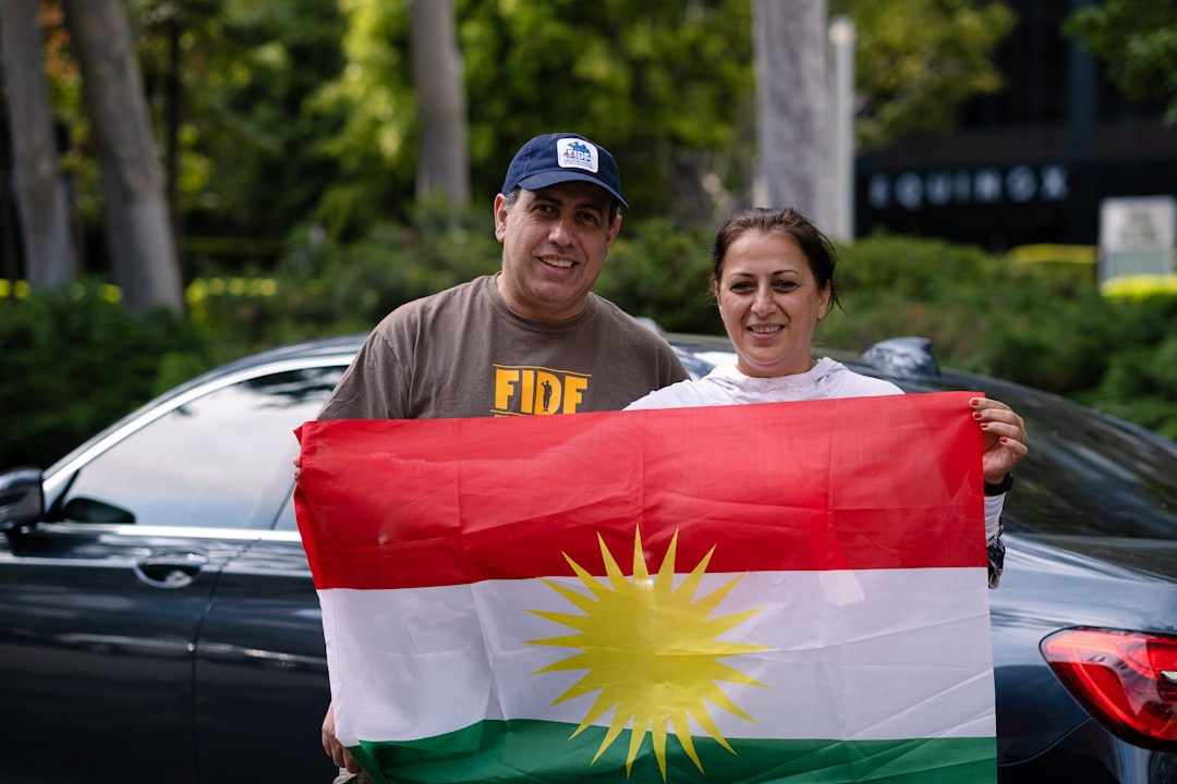 man in brown polo shirt wearing green and yellow hat holding red green and white flag