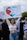 A person holding a protest sign that features a heart design with an Israeli flag motif and the words 'No Más Hamas.' The individual is standing among a group of people, some of whom are carrying additional signs and an Israeli flag.