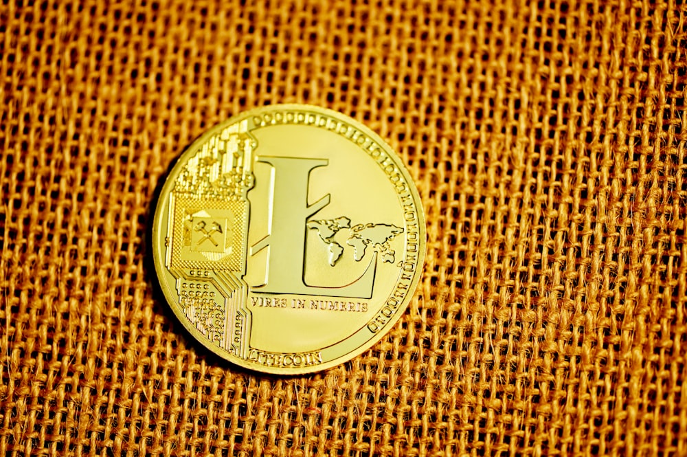 silver round coin on brown textile