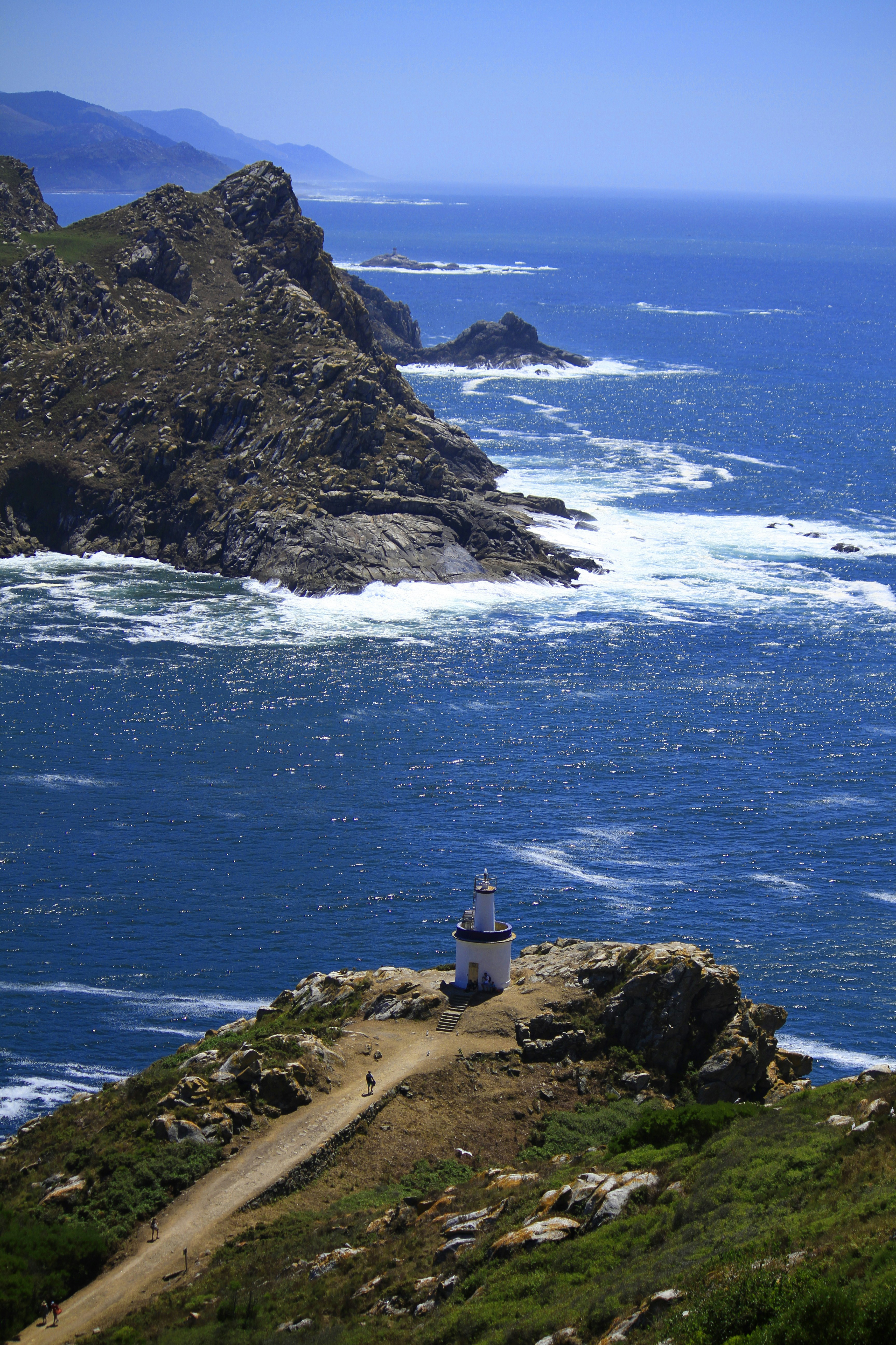white lighthouse on brown rock formation near body of water during daytime