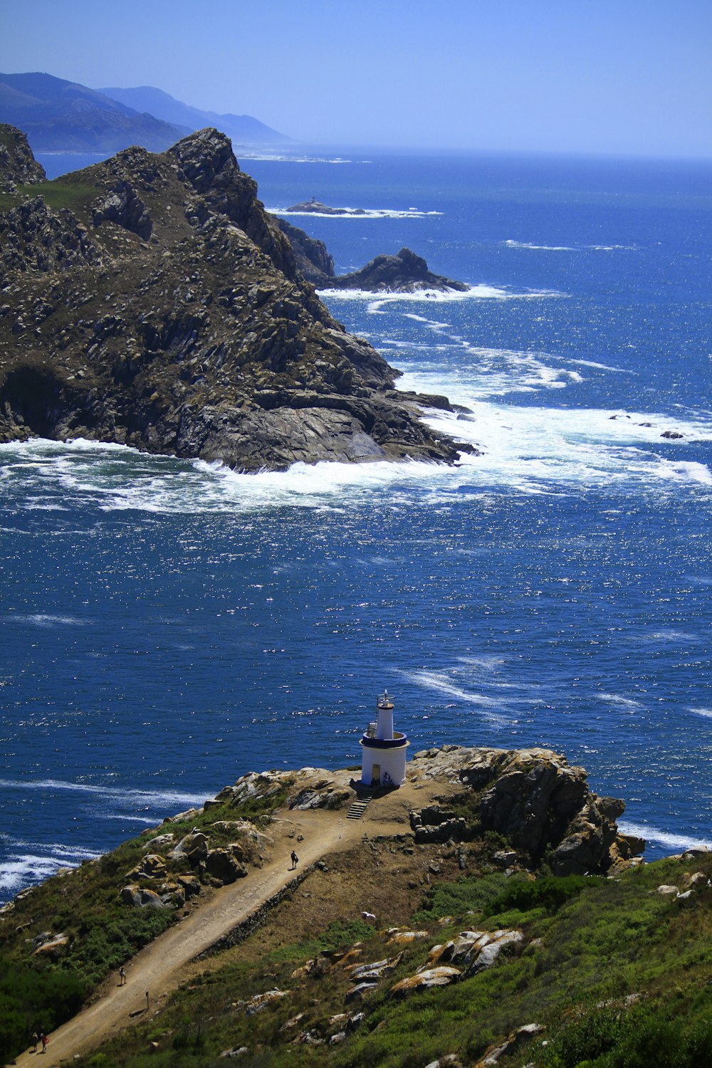 white lighthouse on brown rock formation near body of water during daytime