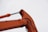 A close-up view of an orange excavator arm with visible hydraulic components against a cloudy sky.