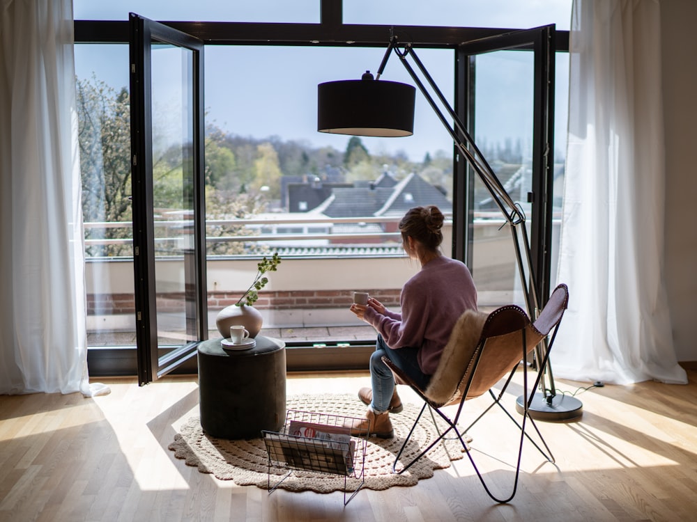 man in pink dress shirt sitting on chair near window during daytime