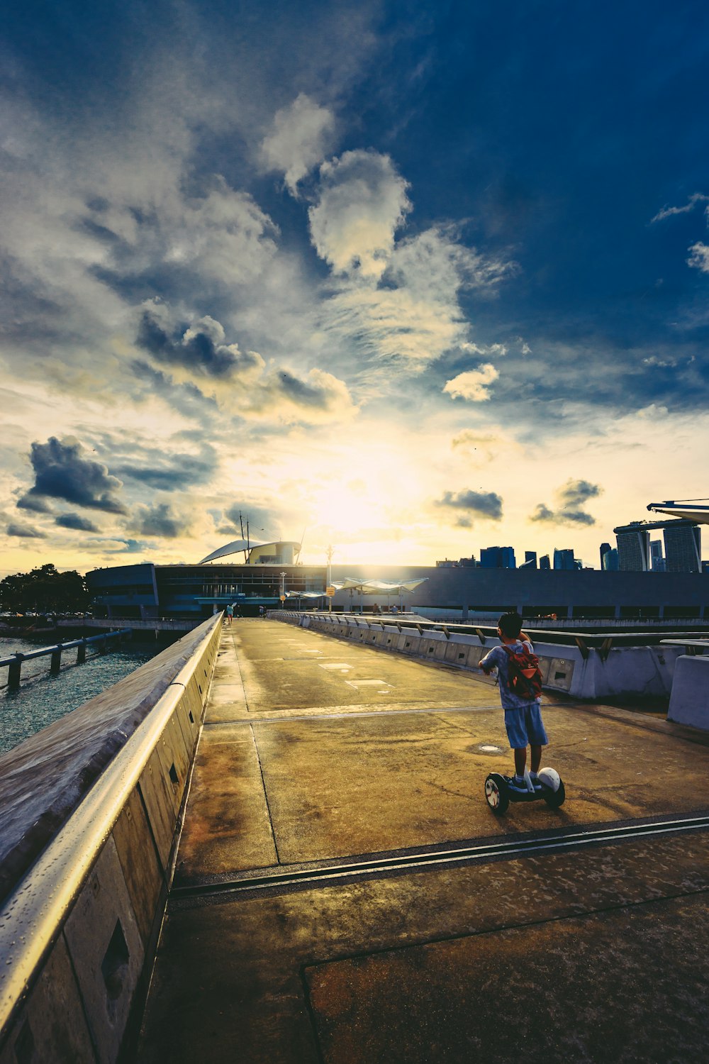 man in white shirt and blue denim jeans riding bicycle on bridge during daytime