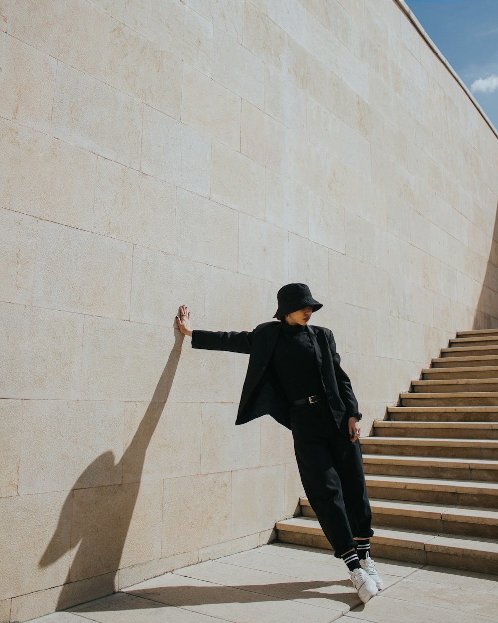 검은 코트와 갈색 바지를 입은 남자가 갈색 콘크리트 계단에 서 있다