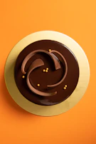 Close-up of a transparent cake box showcasing a rich chocolate cake with glowing gold accents.
