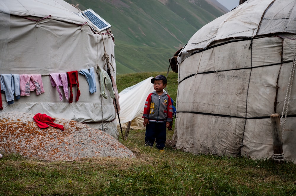 man in blue jacket standing near white tent during daytime