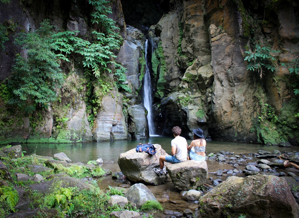 people sitting on rock near waterfalls during daytime