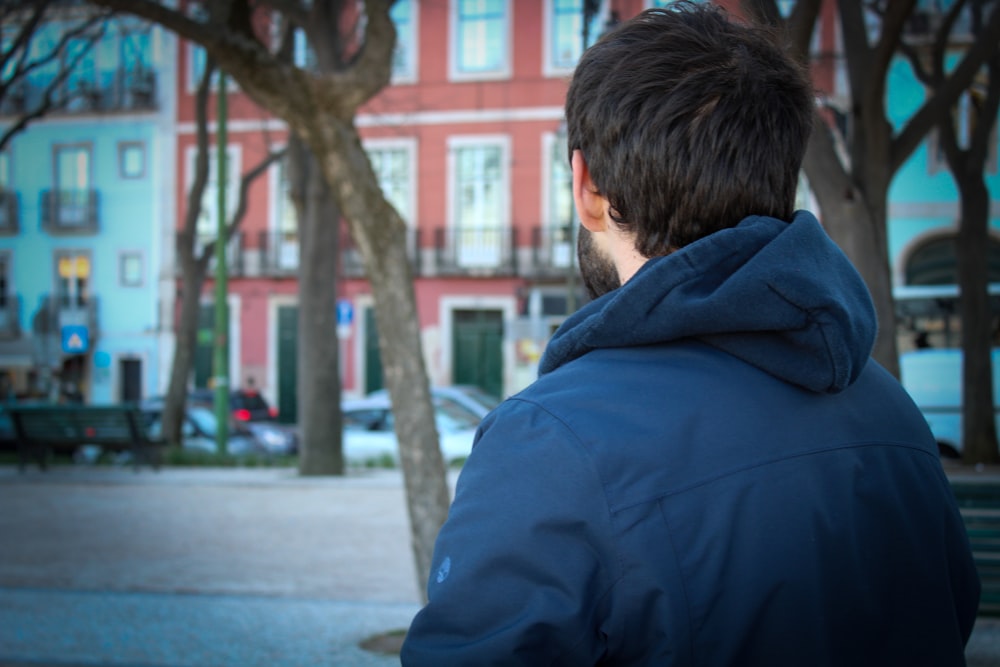man in blue hoodie standing near brown tree during daytime