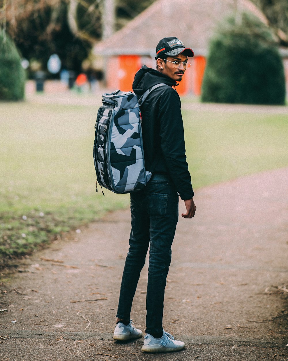 man in black jacket and black pants with black backpack walking on pathway during daytime