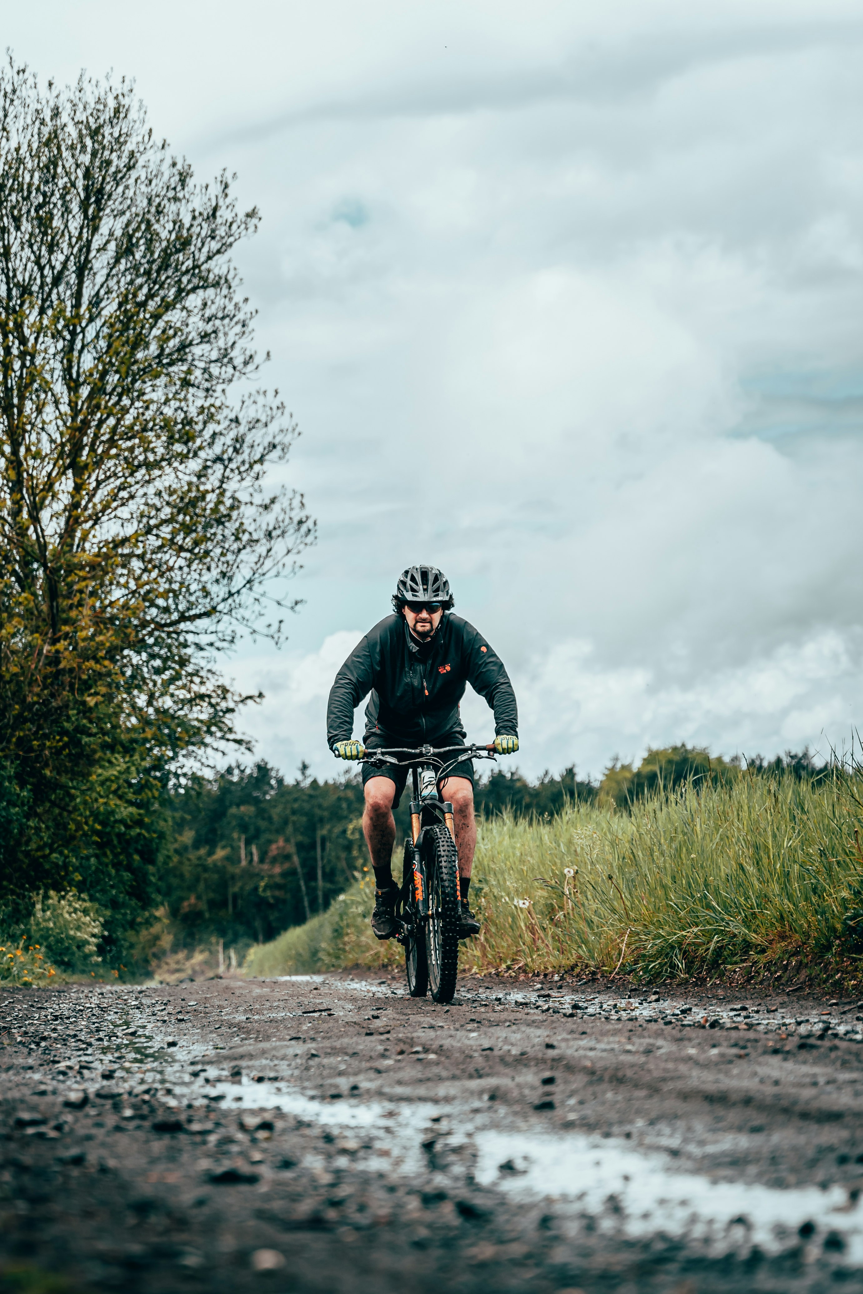 man in black and white bicycle helmet riding on black mountain bike on road during daytime