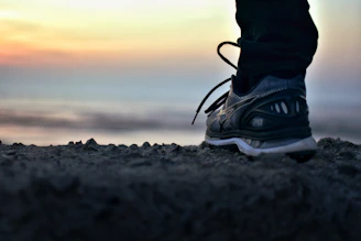 Close-up of running shoes on a trail, with a sunrise in the background.