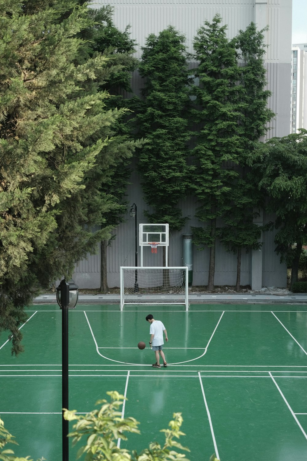 man in white shirt and black shorts standing on basketball court