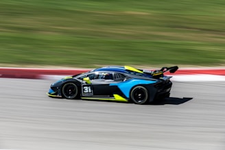 Side view of a sports car wrapped in black with electric blue stripes racing along the body.