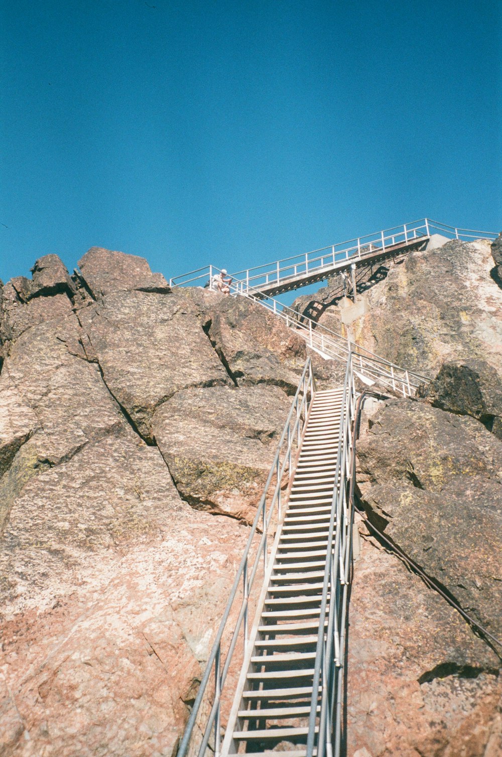 Pont en métal blanc sur la montagne rocheuse brune sous le ciel bleu pendant la journée