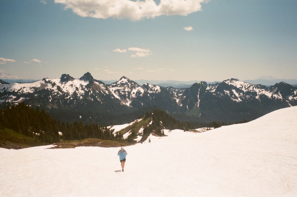 person in white jacket and blue denim jeans walking on snow covered ground during daytime