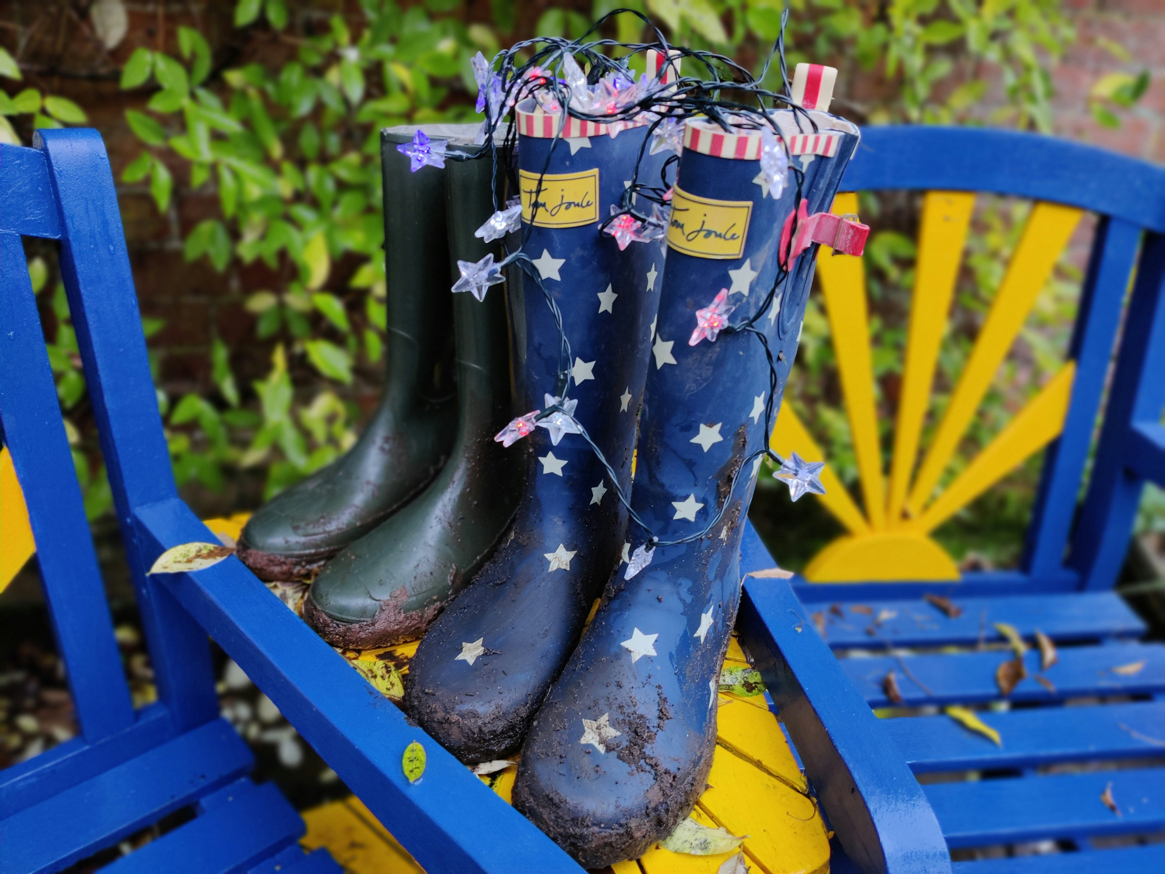 Bottes de pluie marron et noir sur banc en bois bleu