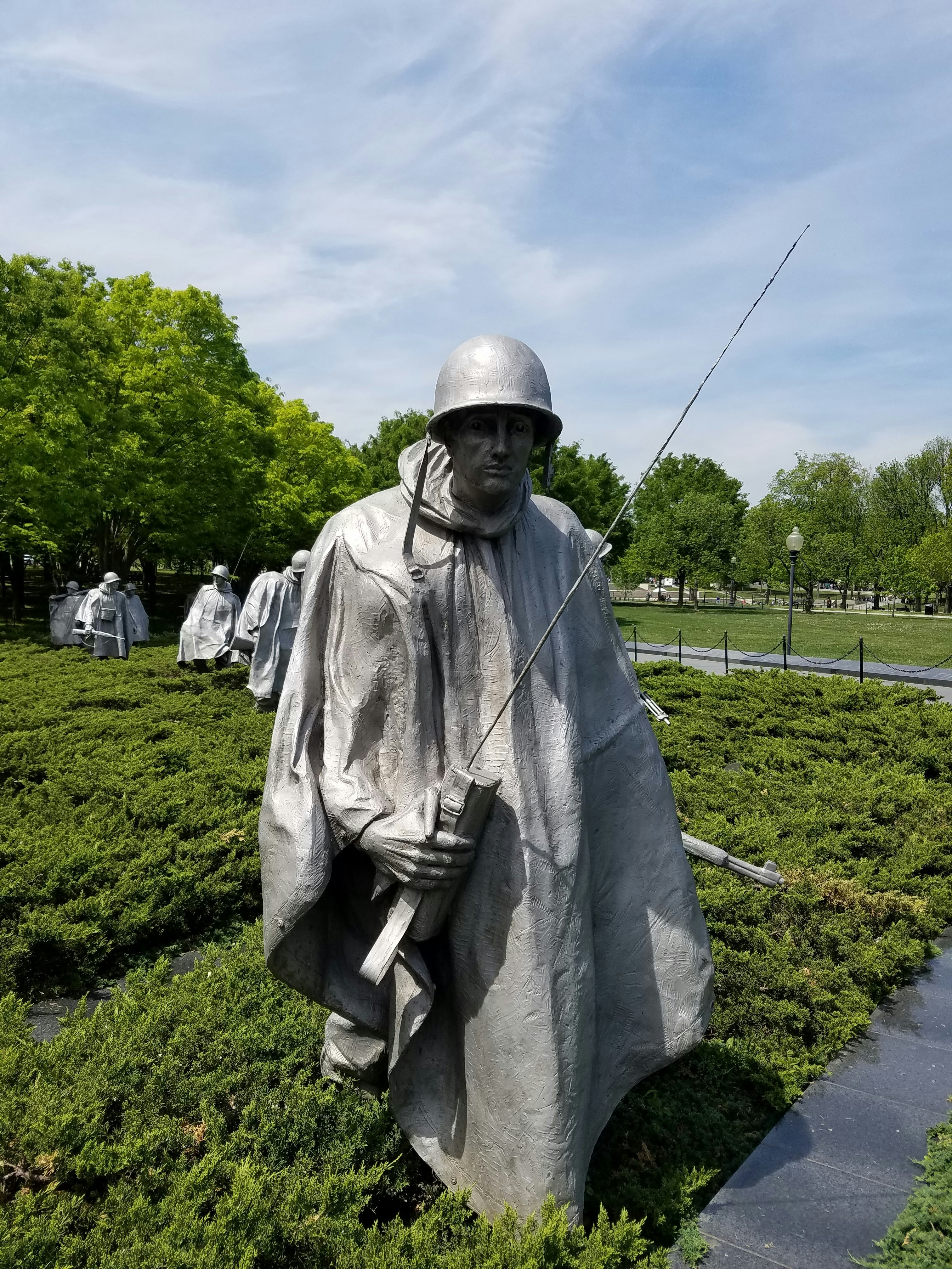 man in gray robe standing on green grass field during daytime