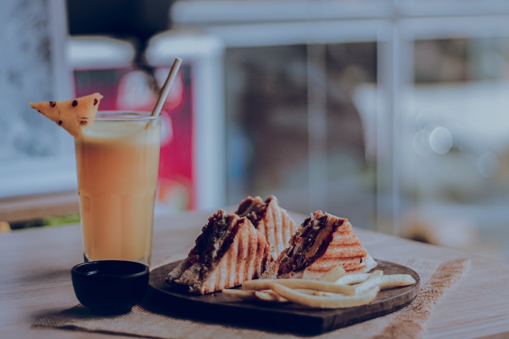 sliced of cake on white ceramic plate beside clear drinking glass with brown liquid