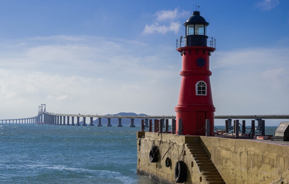 red and white lighthouse near sea under white clouds during daytime