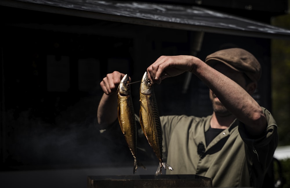 man in brown long sleeve shirt holding fish