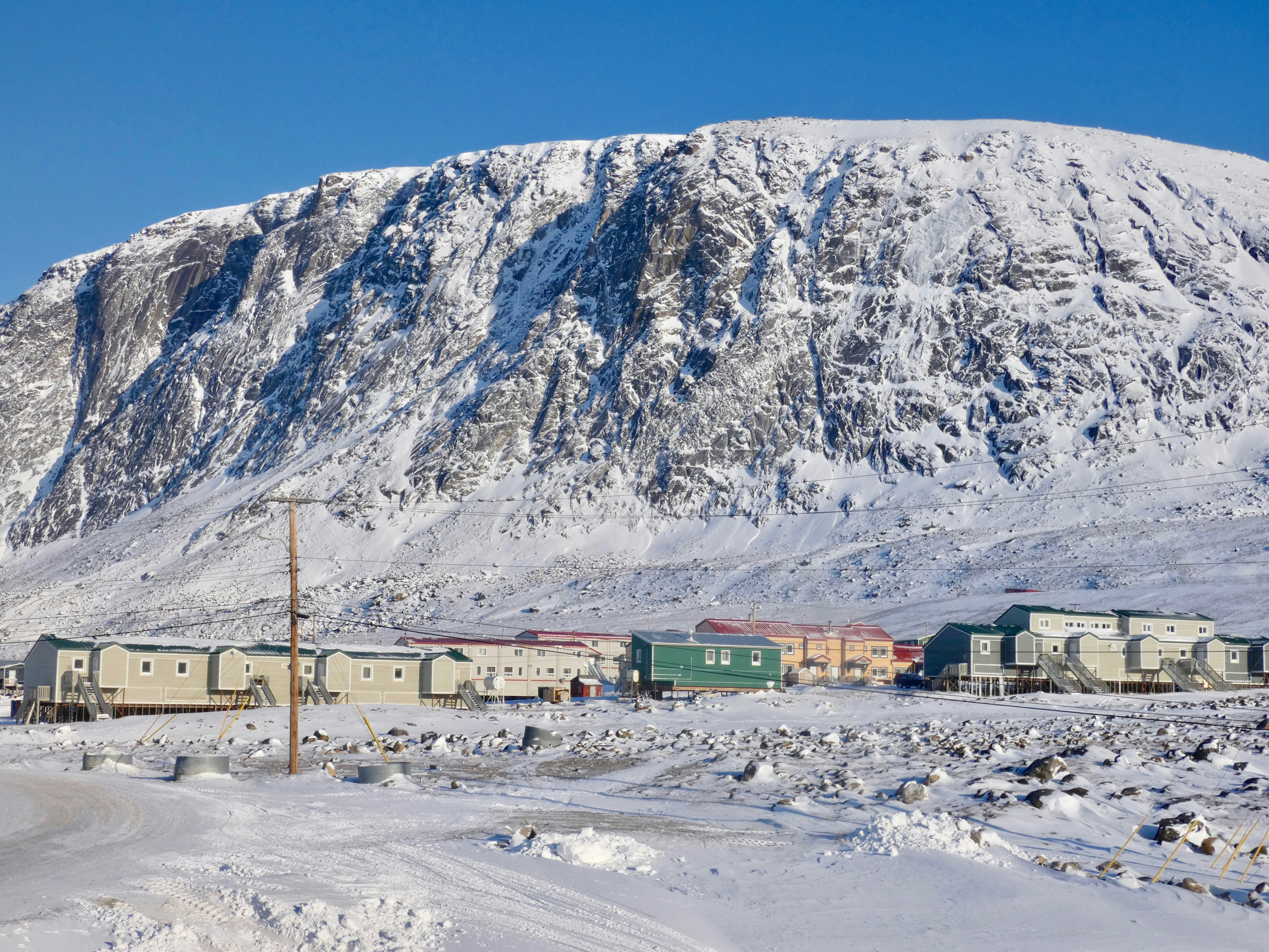 white and brown house near mountain under blue sky during daytime