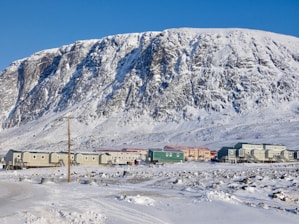 white and brown house near mountain under blue sky during daytime