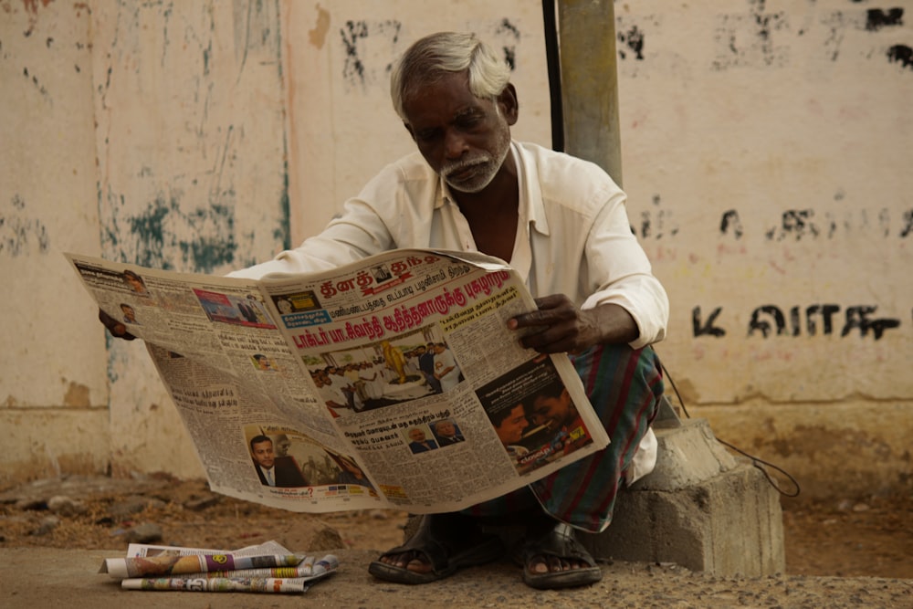 man in white thobe reading newspaper