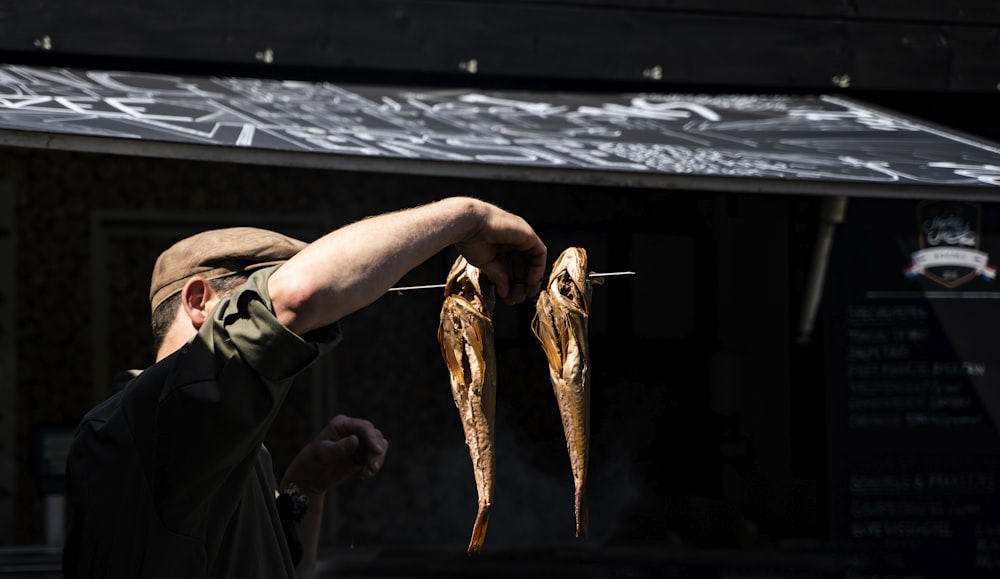 man in green jacket holding a brown fish