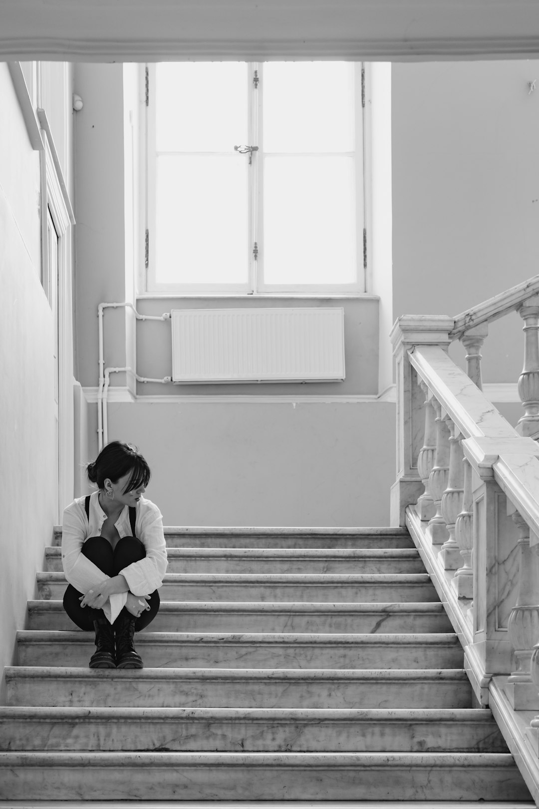 grayscale photo of woman sitting on staircase