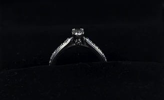 Close-up of a sleek, modern silver ring with a matte finish resting on a dark velvet cushion.