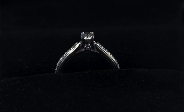 Close-up of a sleek, modern silver ring with a matte finish resting on a dark velvet cushion.