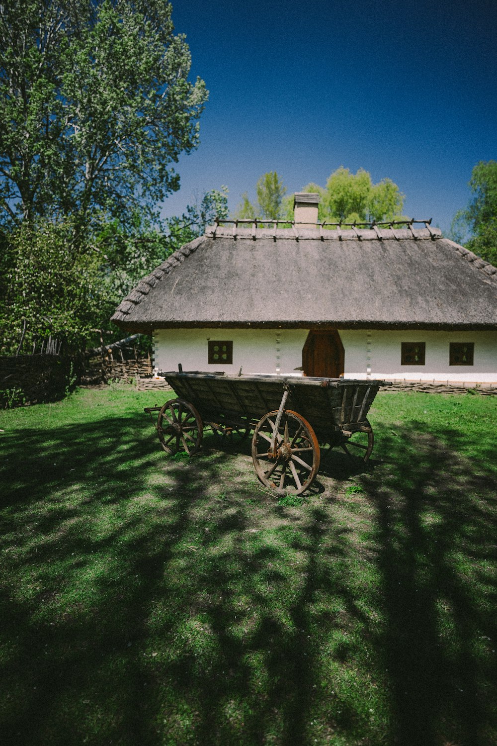 brown wooden cart on green grass field near green trees during daytime