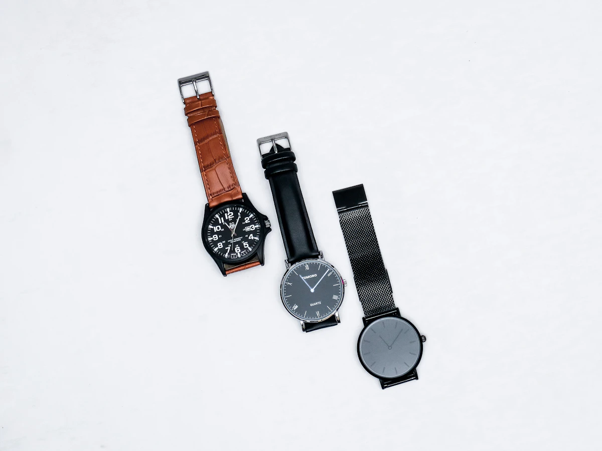 Two analog watches, one black and one brown