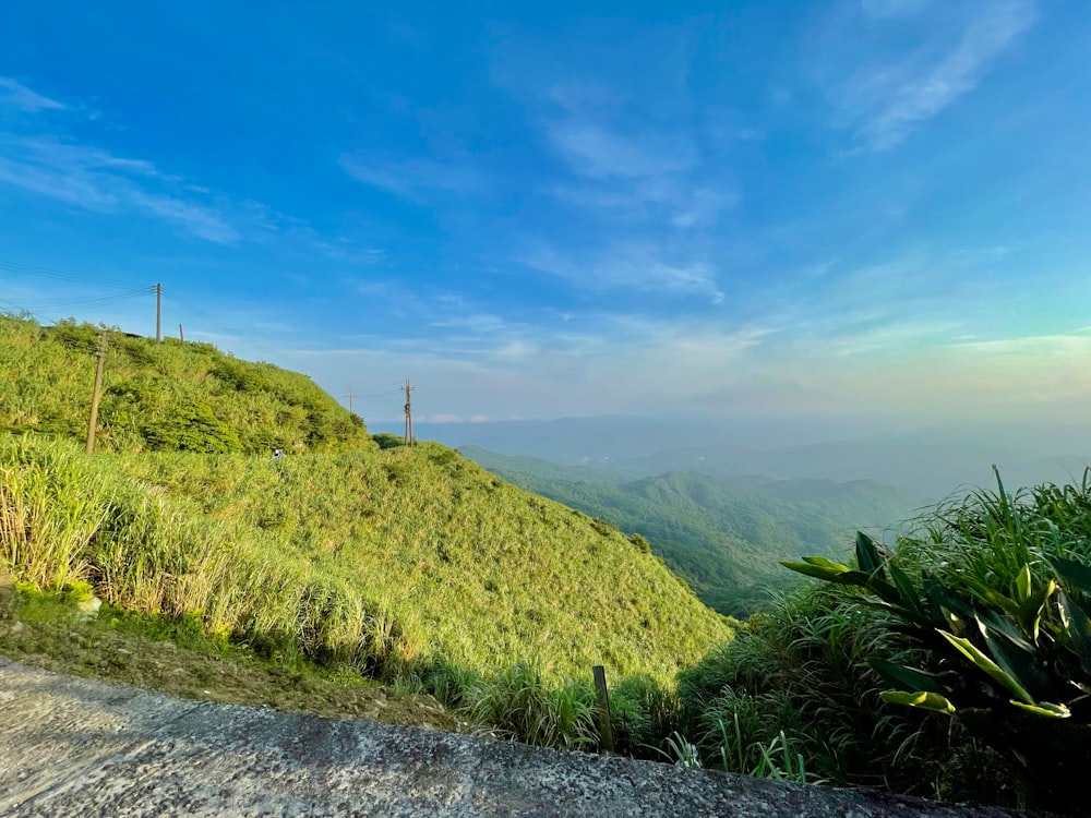 green grass field near mountain under blue sky during daytime