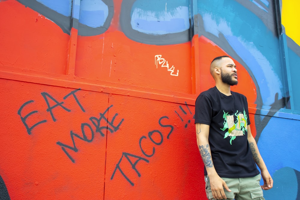 man in black crew neck t-shirt standing beside red wall