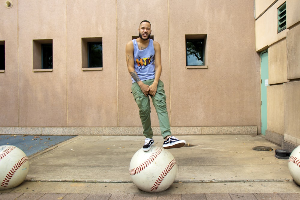 man in blue tank top and green pants holding white soccer ball