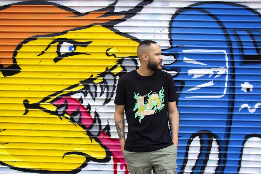 man in black crew neck t-shirt standing beside yellow and blue surfboard