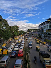 A busy Chennai street scene showing cars, shops, and industrial buildings under a clear sky.