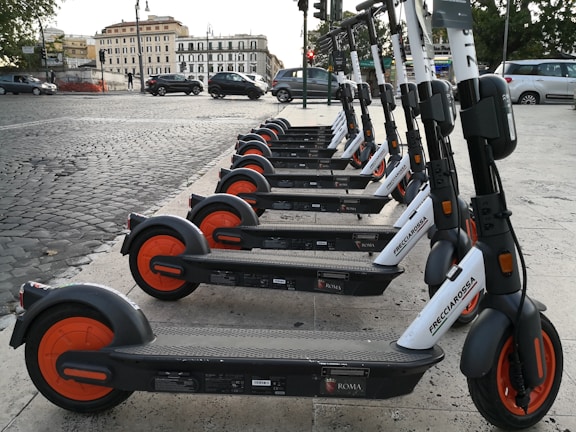 A group of electric scooters lined up in a vibrant city.